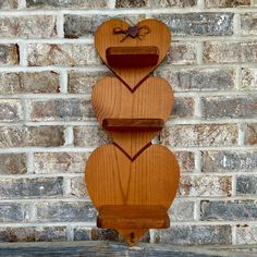 two wooden heart shaped shelves against a brick wall