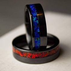 two wedding rings with blue and red opal inlays on each ring band