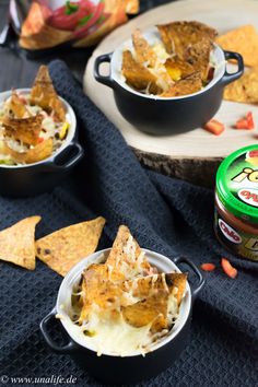 three bowls filled with nachos and chips on top of a blue table cloth