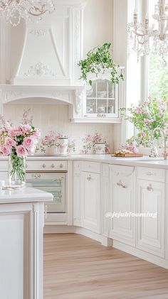 a kitchen with white cabinets and pink flowers