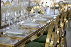 the table is set with white flowers and gold trimmings, along with green velvet chairs