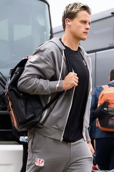 a man in grey sweatpants carrying a black backpack and headphones on his ear