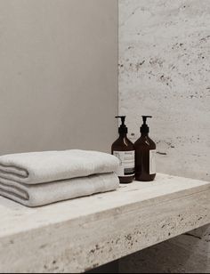 towels and soaps are sitting on a wooden shelf in front of a white wall