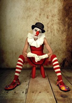 a clown sitting on top of a wooden floor