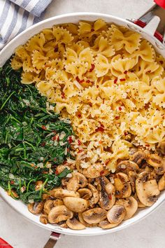 a bowl filled with pasta, spinach and mushrooms