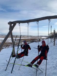 two skiers sitting on swings in the snow