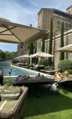 people are lounging on the grass near an outdoor pool