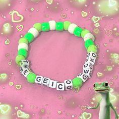 a green and white beaded bracelet with the word geico on it next to a frog