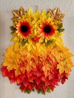 an owl made out of leaves and sunflowers on a white wall next to a painting