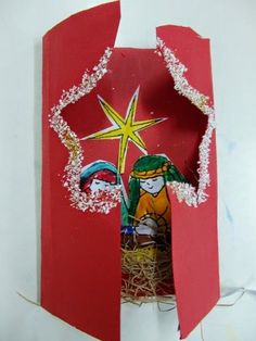 an open red paper bag with a nativity scene in the center and star on top