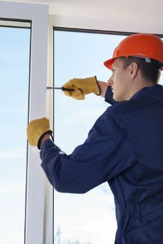 a man in an orange safety helmet and yellow gloves is working on a window sill