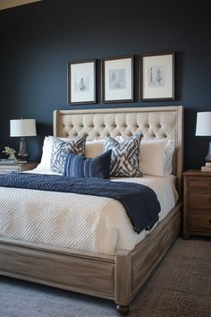 a bedroom with blue walls, white bedding and two framed pictures on the wall