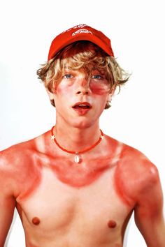 a shirtless young man wearing a red hat