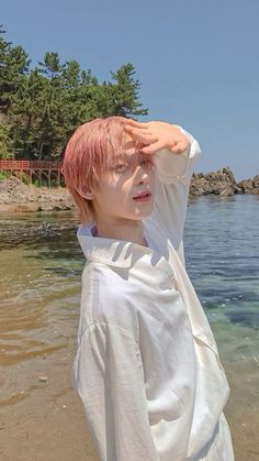 a person standing on top of a beach next to the ocean holding their hands up