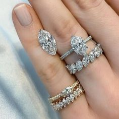 a woman's hand with three different rings on her fingers and one is holding the other