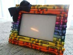 a multicolored photo frame made out of crayons with a black bow