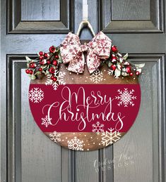 a merry christmas door hanger on a front door with red and white snowflakes