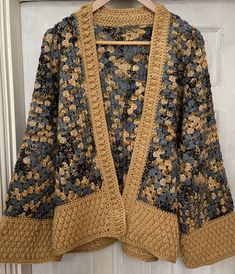 an open knit cardigan sweater hanging on a hanger in front of a door