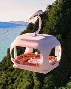 a cable car suspended over the ocean with an outdoor seating area on it's side