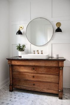 a bathroom vanity with a round mirror above it