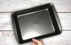 a person is holding up a black square tray