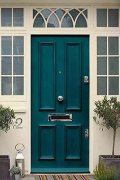 a green front door with two potted plants on the side and an entry mat