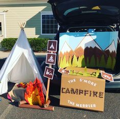 an open car trunk with campfire signs on the side and a teepee tent next to it