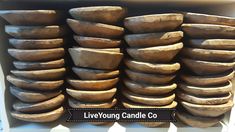 a large stack of wooden bowls sitting on top of a counter next to a sign