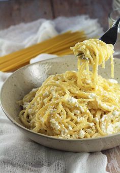 a bowl filled with noodles and cheese being held by a fork