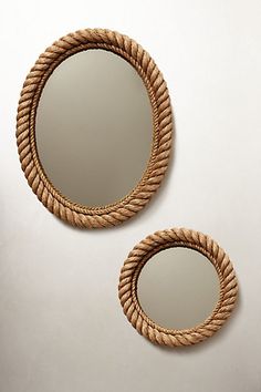 two round mirrors sitting next to each other on a white surface with rope around them