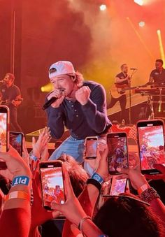 a man standing on top of a stage surrounded by people holding up their cell phones