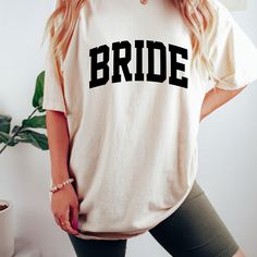 a woman standing in front of a plant wearing a t - shirt that says bride