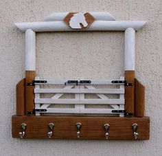 a white and brown wooden fence with hooks on the wall next to it is an image of a horse