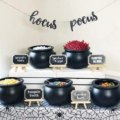 a table topped with black bowls filled with candy and popcorn next to chalkboard signs