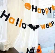 halloween decorations are hanging on the window sill in front of a white curtain with happy halloween written across it