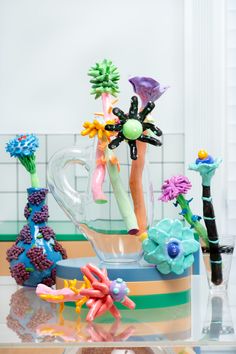 a vase filled with different colored flowers on top of a glass table next to a tiled wall