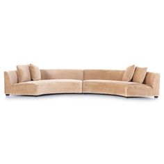 a curved couch with pillows on the top and bottom, sitting in front of a white background