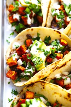 three tacos are on a tray with toppings