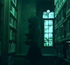 a woman standing in front of a book shelf filled with books