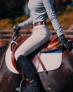 a woman riding on the back of a brown horse