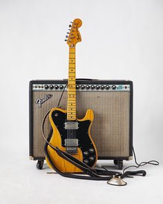 an electric guitar, amp and headphones sit on a white background next to each other