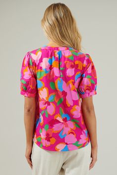 You'll be thriving all day long when you step out in the Daphne Floral Neli Split Neck Top! It has a gorgeous pink multi floral design all over. This classic top t has short puff sleeves followed by a split neckline that forms into V-neck. Wear it with high waisted white pants or matching pink pants for a stylish fit! - Split neck- Puff sleeves- Breathable- Relaxed fit- Color: Fuchsia MulSize + Fit - Model is 5'8" and wearing size XS- Measurements taken from size S - Chest: 20 1/4"- Length: 24 3 Multicolor Floral Print Short Sleeve Blouse, Spring Short Sleeve Multicolor Print Blouse, Feminine Tops With Vibrant Print For Spring, Feminine Floral Print Short Sleeve Top, Feminine Short Sleeve Floral Print Top, Short Sleeve Multicolor Print Blouse For Spring, Feminine Multicolor Short Sleeve Blouse, Spring Pink Top With Vibrant Print, Pink Vibrant Print Top For Spring