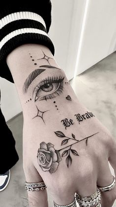 a woman's hand with an eye and rose tattoo on it