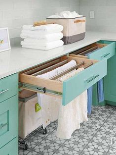 an open drawer in the middle of a kitchen with towels hanging on it's sides