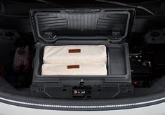 the back end of a white car with its trunk open and two seats folded up