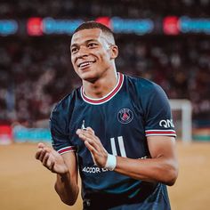 a man standing in front of a soccer field with his hands together and smiling at the camera