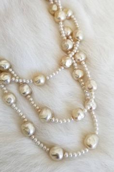 "This is a vintage 1940's Original by Robert necklace. The stands are made from hand painted glass beads made to look like baroque style pearls. They have a variety of color tones from ivory to off white from age and previous wear. They have been restrung in a previous ownership and one of the strands was mis-strung and overlaps with another strand. The clasp has a chipping on one of the hand-painted pearls. The clasp has pearl tone beads, AB rhinestones, and clear rhinestones. The signature is Elegant Cream Jewelry With Large Beads, Pearl White Round Beads Necklace For Evening, Silver Pearl Necklace With Large Beads, Vintage Long Pearl Necklace, Large Beads Pearl Necklace For Jewelry Making, Evening Pearl Necklace With Round Beads, Elegant Large Bead Pearl White Necklace, Elegant Large Beaded Pearl White Necklace, Elegant Cream Necklaces With Large Beads