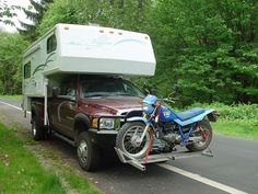 a motor home is parked next to a motorcycle on the side of the road in front of a truck