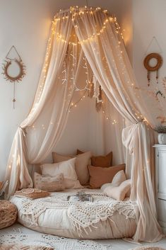 a canopy bed with lights hanging from it's sides and pillows on the floor