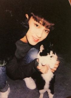 a young man holding a black and white cat